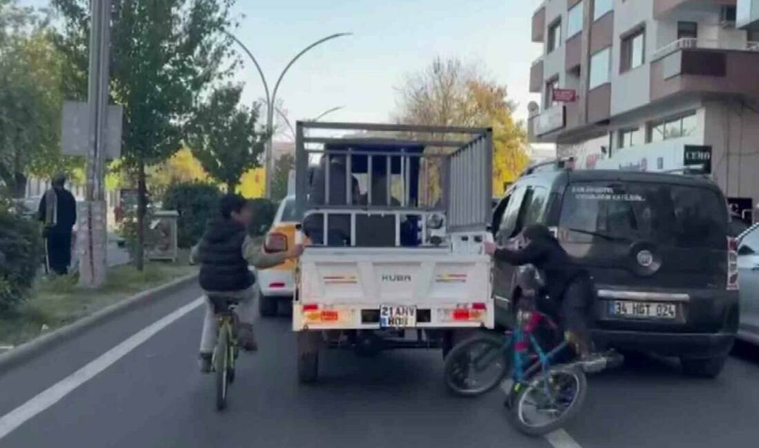 Diyarbakır'ın Yenişehir ilçesinde bisikletli iki çocuk, sepetli motora tutunarak tehlikeli