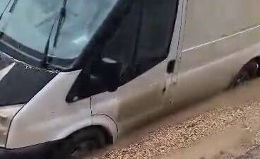 Adıyaman’da yoğun yağışların ardından yolda oluşan çukura saplanan bir minibüs