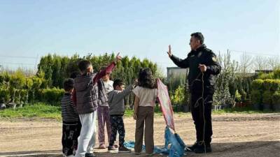 Mardin'de yağışların durmasıyla sokaklara çıkan çocuklar uçurtma uçururken, bir polis